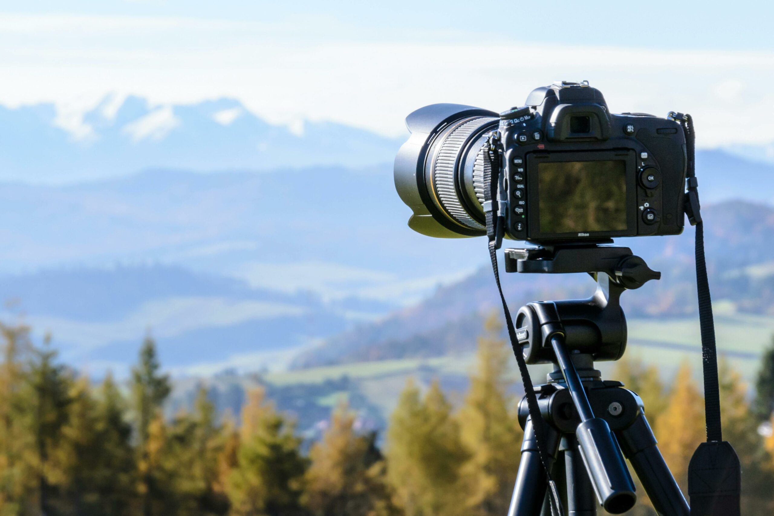 A camera mounted on a tripod is pointing at a mountainous landscape